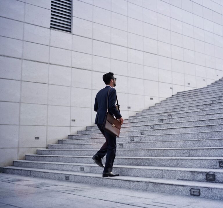 Ein Mann in Anzug läuft eine große Steintreppe hinauf.