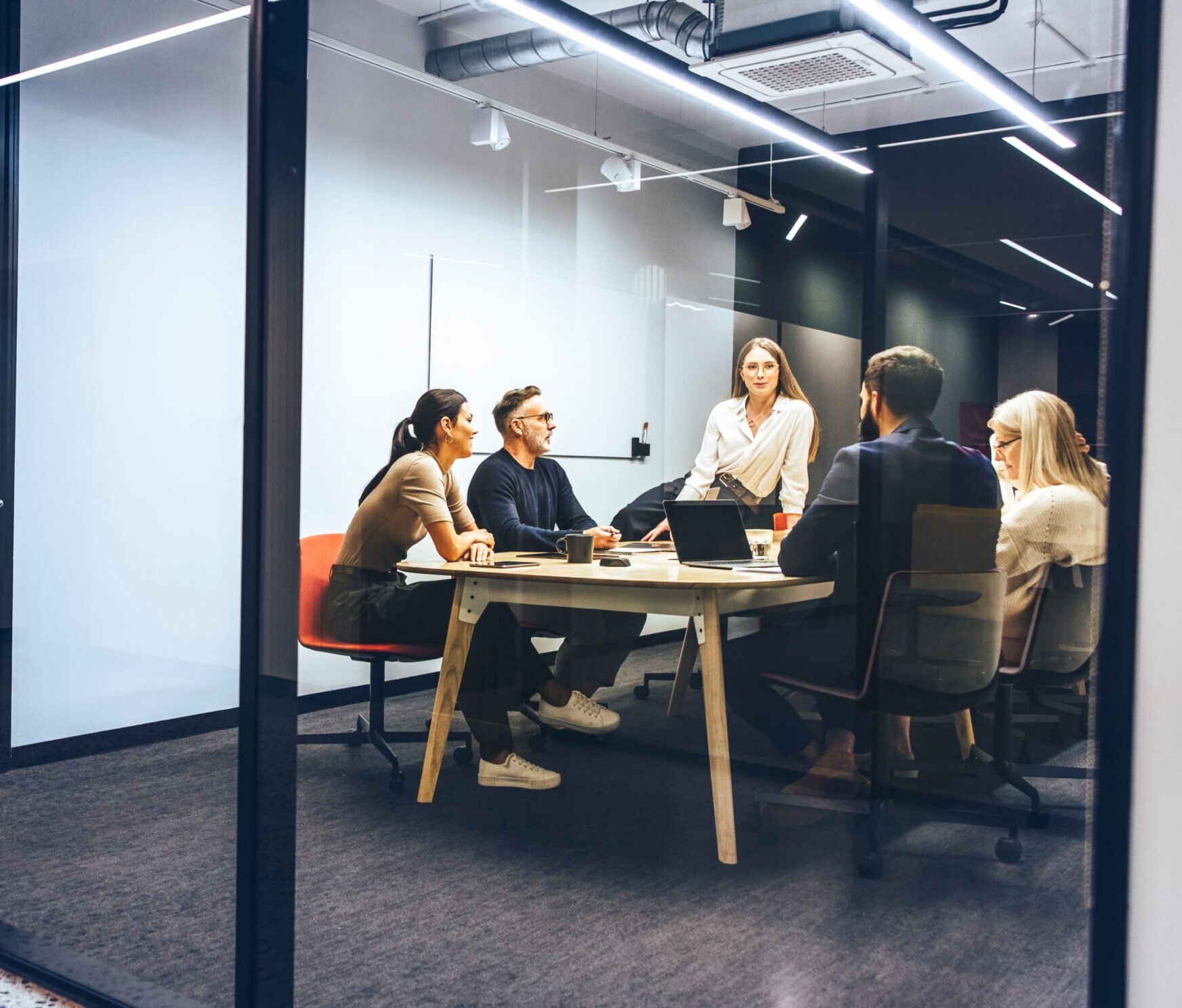 Eine Gruppe von Führungskräften plant in einem gläsernen Büro eine Mitarbeiterbefragung.